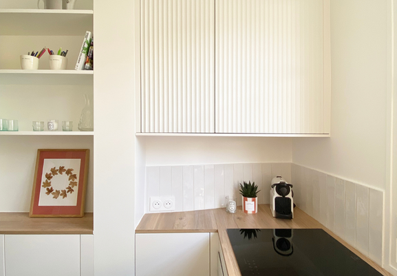 Une cuisine blanche avec des façades blanches et un plan de travail en bois