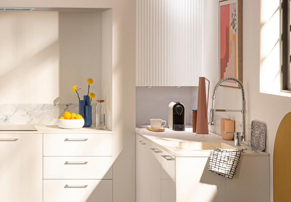 Une cuisine blanche avec des façades lisses en bas et ondulées sur les meubles hauts